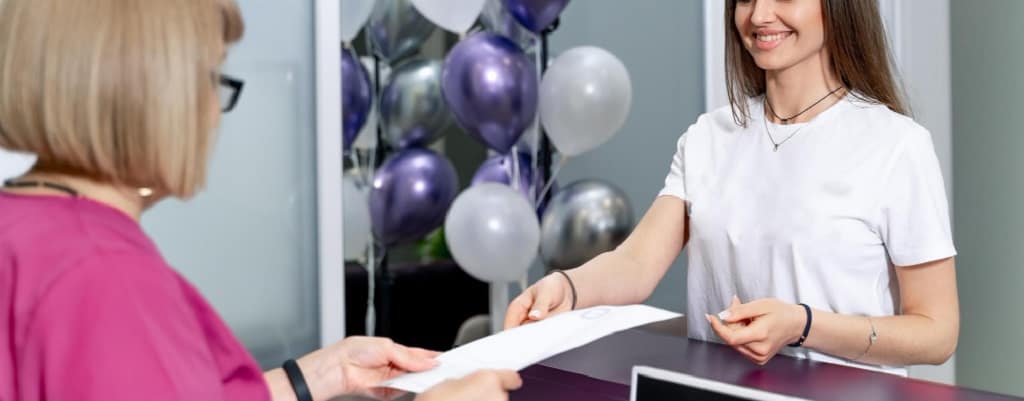 secrétaire médicale qui donne un document à une patiente