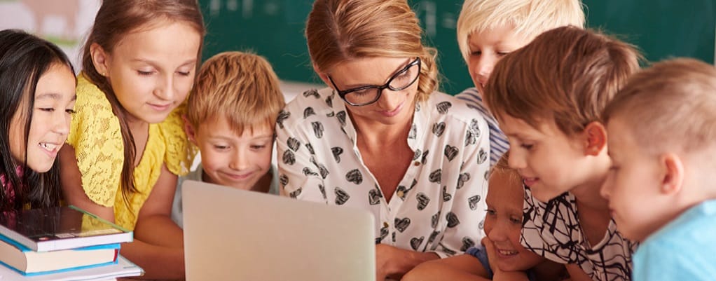 enfants avec leur professeure devant un ordinateur