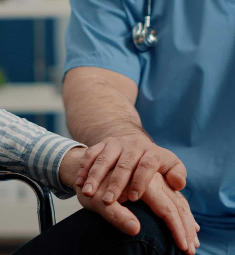Soignant tenant la main d'une personne âgée
