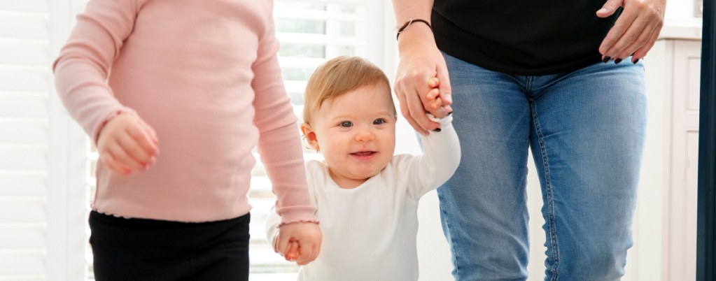 un bébé marchant tenu par les mains