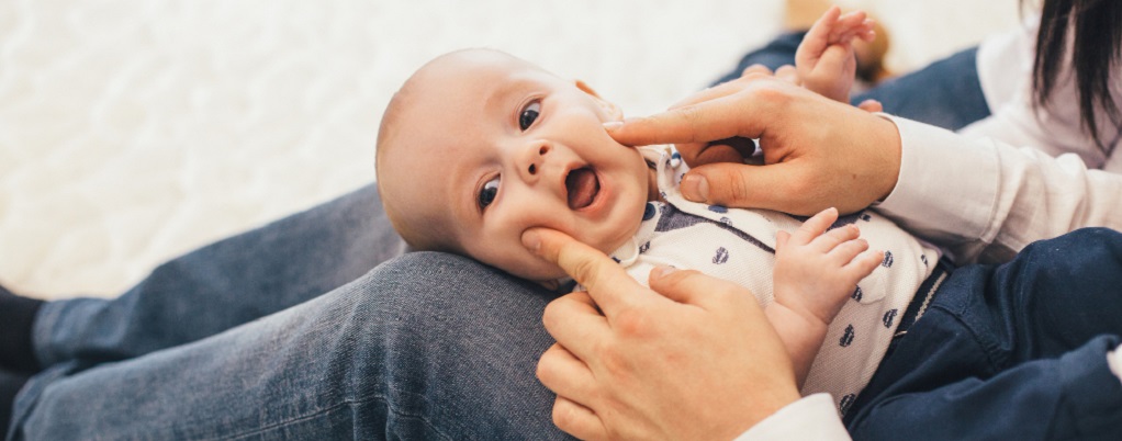 un bébé souriant sur les genoux de sa maman