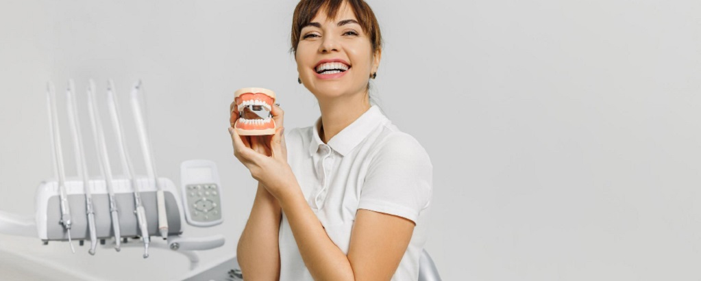 une secrétaire dentaire tenant un dentier dans ses mains