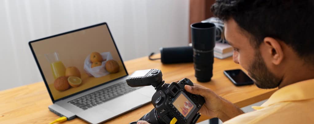 un photographe avec son appareil travaillant sur son ordinateur portable