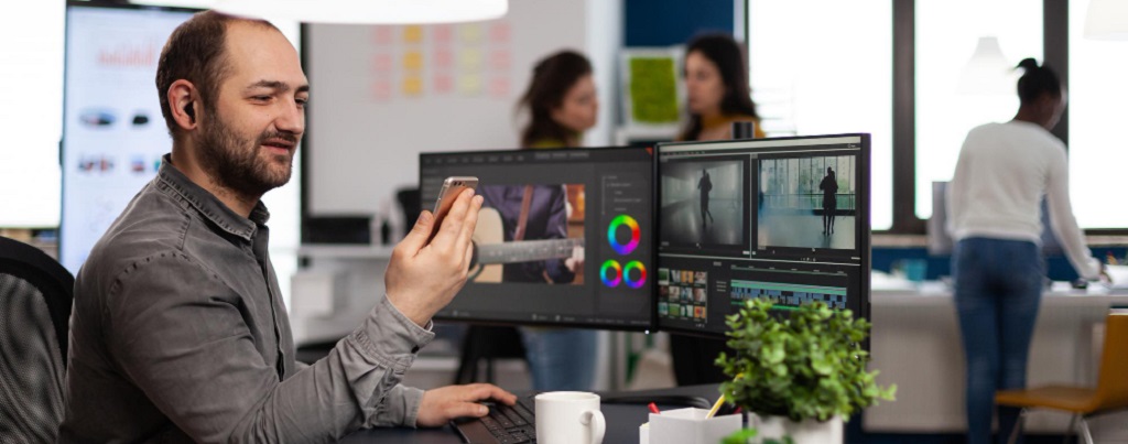 un homme à son bureau travaillant sur un logiciel de montage vidéo