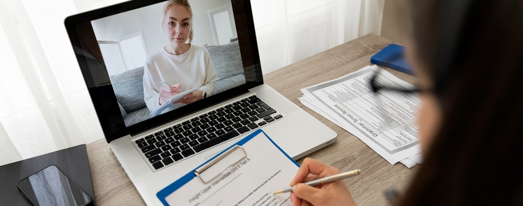 une personne devant son ordinateur suivant une formation et écrivant sur une feuille