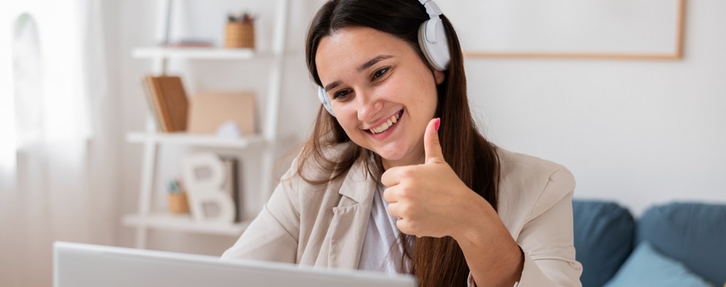 une jeune femme levant le pouce devant son ordinateur portable