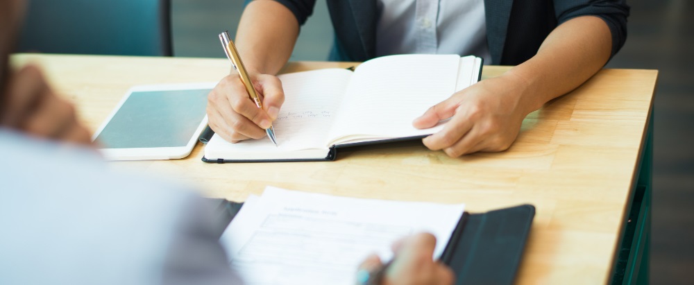 une personne à son bureau écrivant sur un cahier