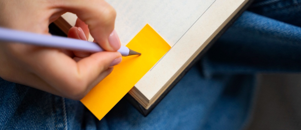 une personne écrivant sur un cahier pour un concours d'ATSEM