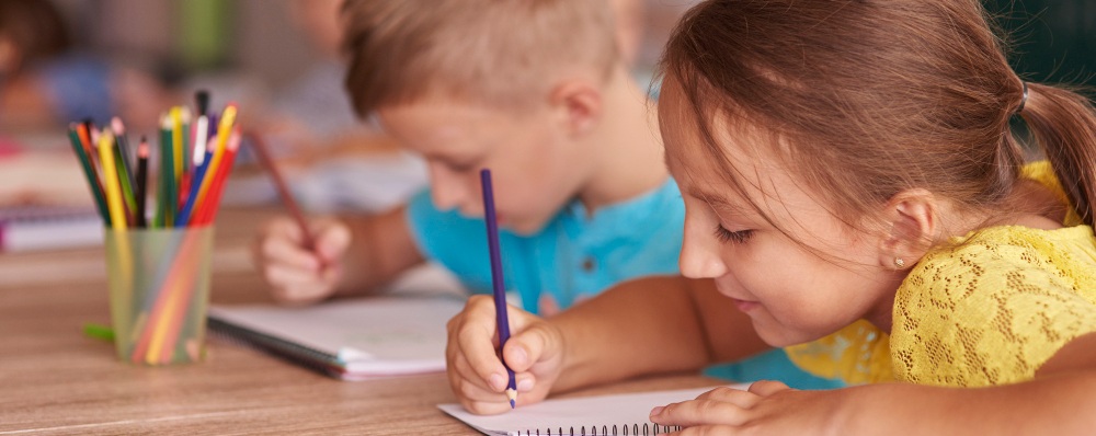 deux enfants dessinant ensemble sur un bureau