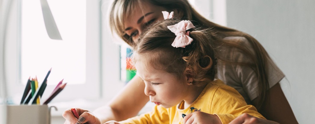 Une ATSEM avec un enfant dessinant