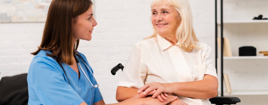 une auxiliaire de vie en blouse bleue avec une personne agée