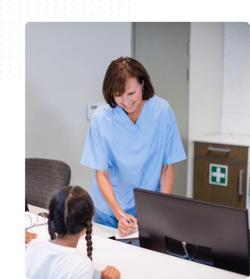 Femme souriante étudiant à distance depuis sa cuisine, carnet et ordinateur devant elle