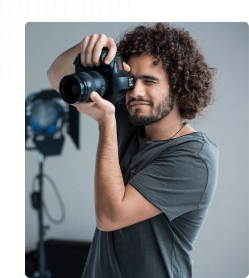 Photographe prenant une photo avec un appareil reflex dans un studio, illustrant les métiers de la photographie