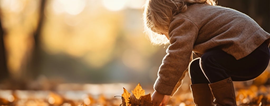 une petite fille ramassant des feuilles dehors en automne